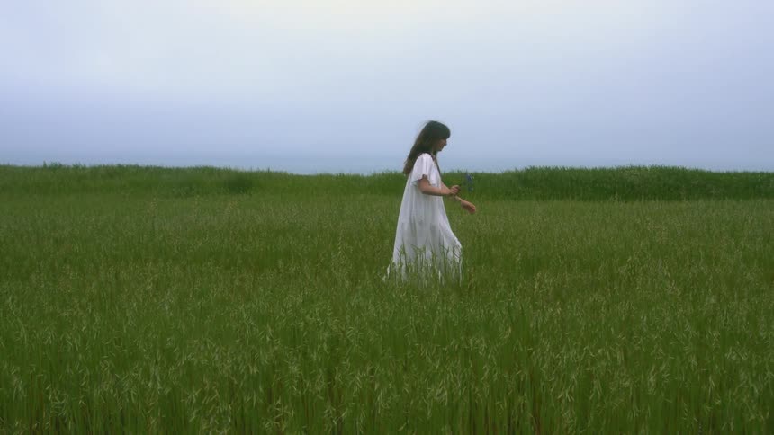 A woman is posing in the field of grass