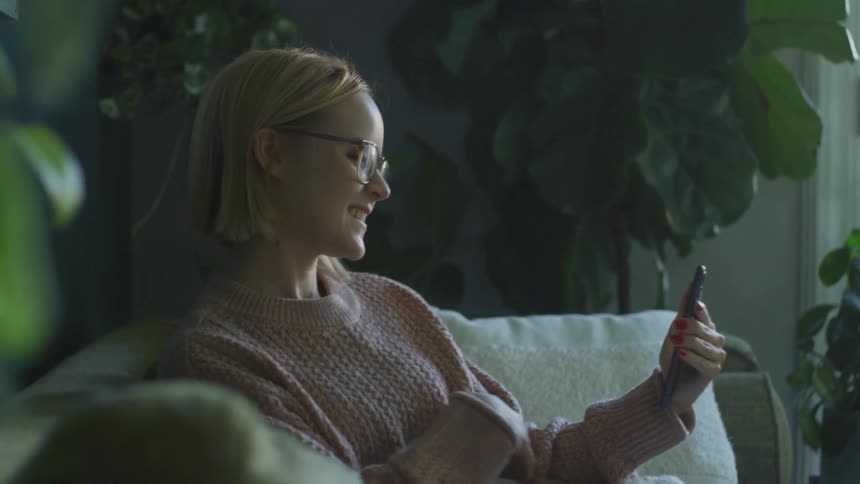 A woman smiles as she talks on a video call on her cell phone