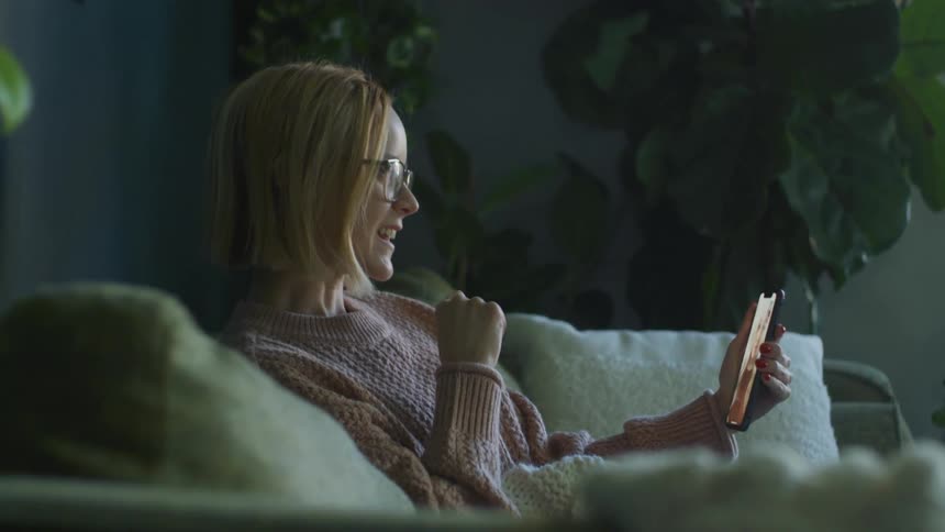 A woman is talking on video phone on her couch
