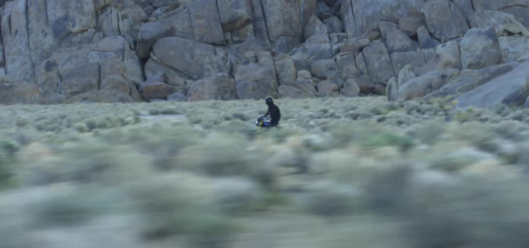 A person is racing in the desert on their dirt bike