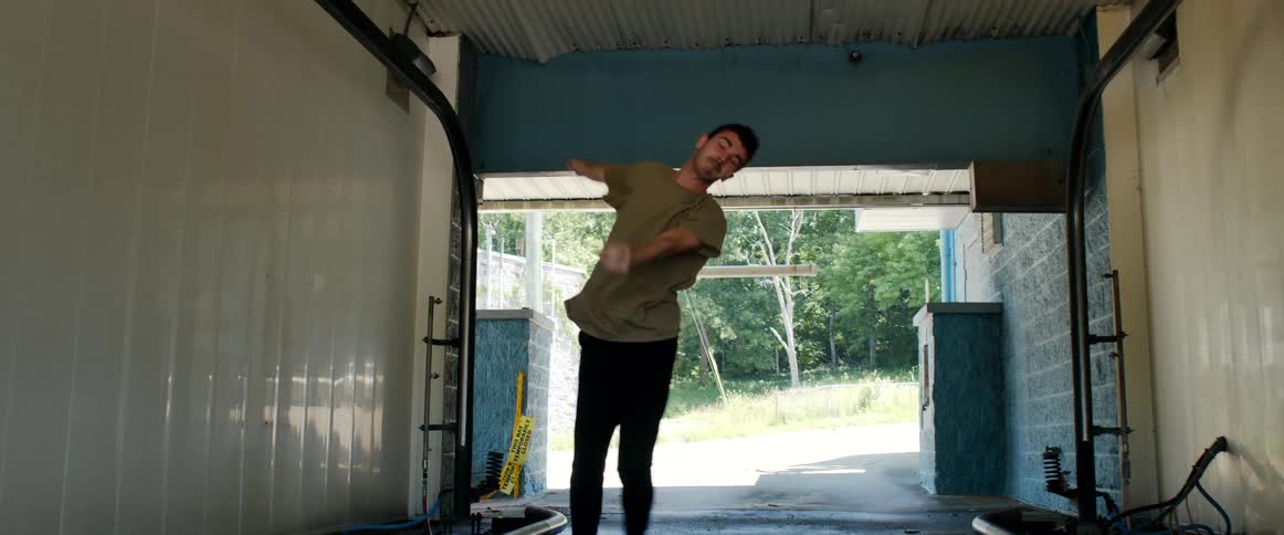 A man dances inside an empty car wash tunnel