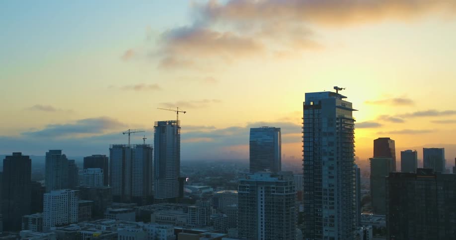 The sun is setting in the horizon of a downtown city