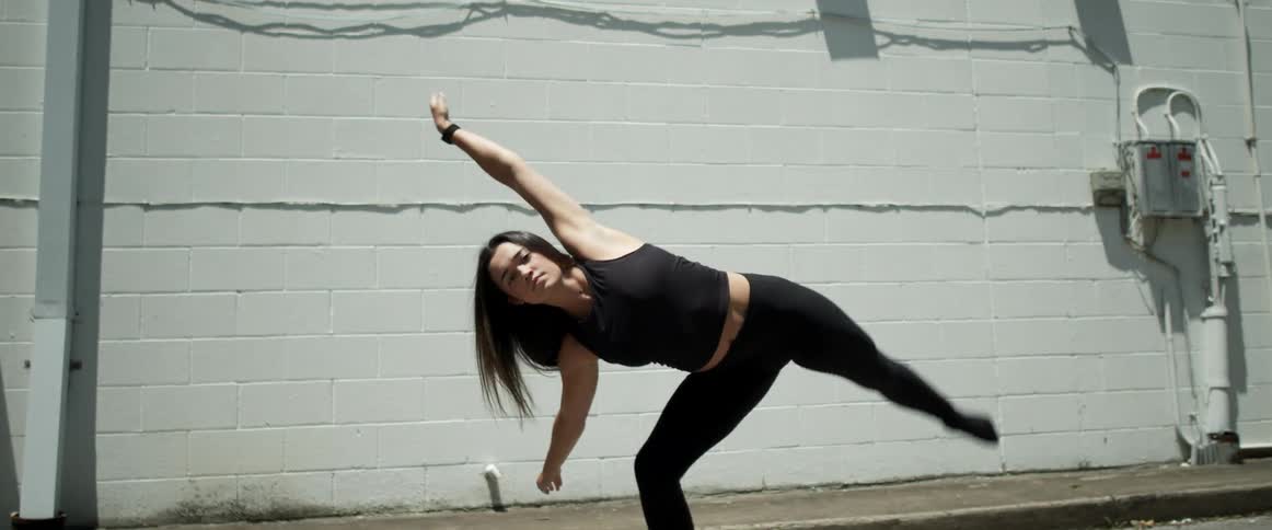 A woman dancing with a wall in the background
