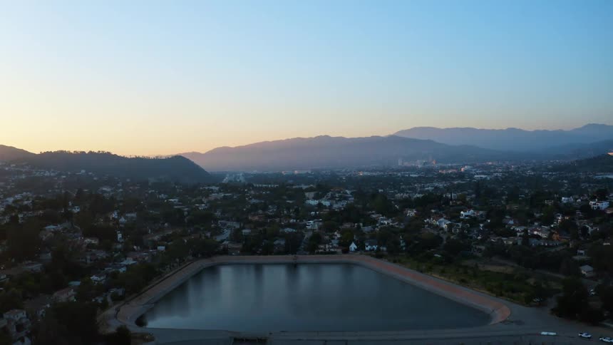 Aerial view of a water reservoir in the middle of a small town at sunset