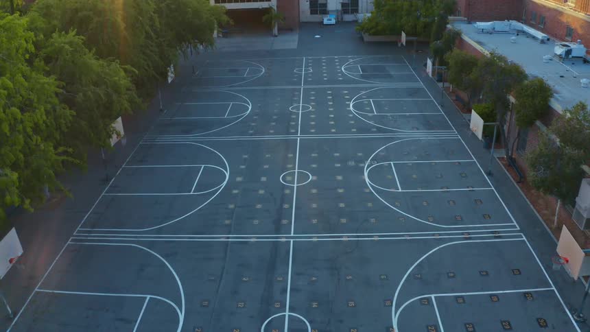 Buildings and trees surround several freshly painted basketball courts