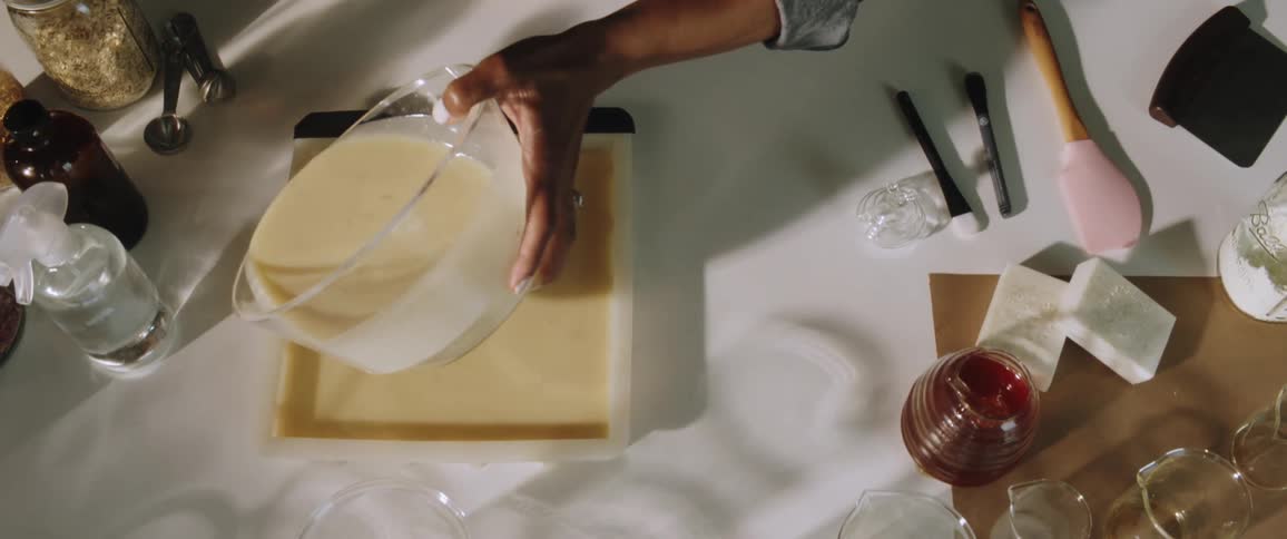 A person pours a batter from a bowl into a square pan