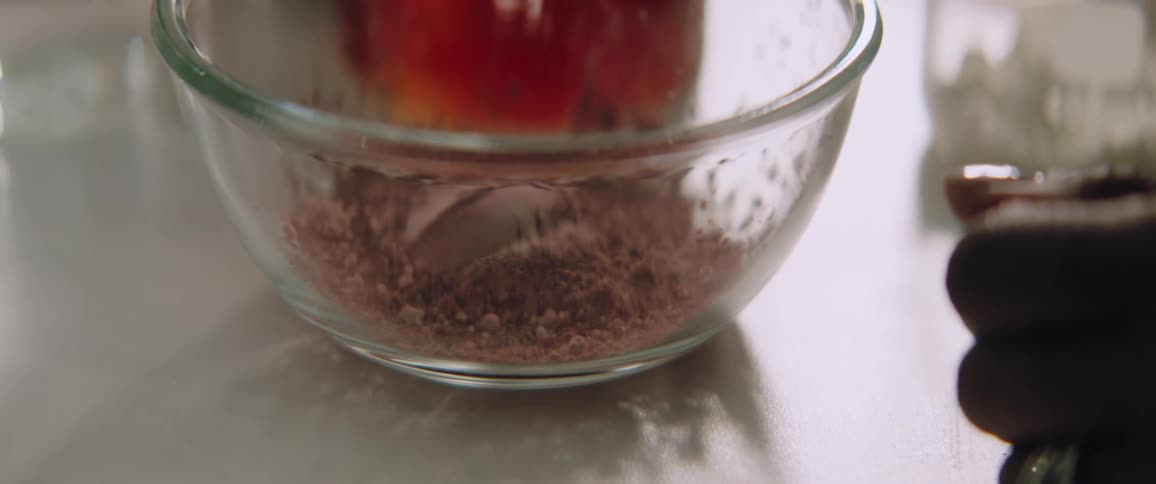 A woman in a room next to a table with a bowl with a brown powder