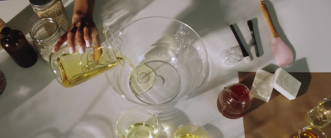 Woman pours yellow liquid into a large clear glass bowl