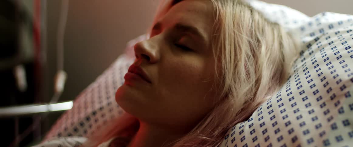 A woman sleeps in a hospital bed with an iv next to it