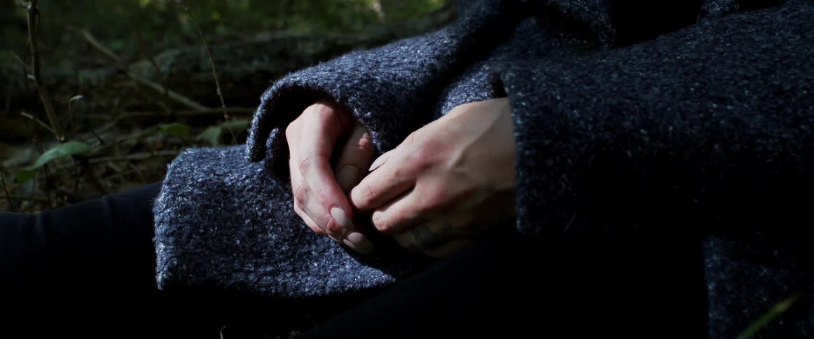 A person sitting outside while wearing a blue jacket