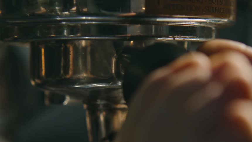 Fingers turn the handle on an espresso machine