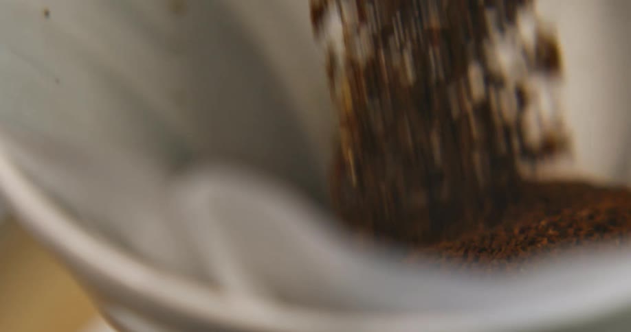 Coffee grounds are poured into a conical filter