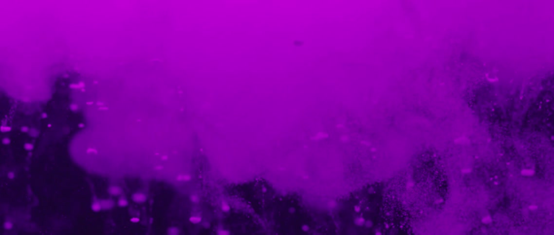 Purple dye floats down and spreads against a black background