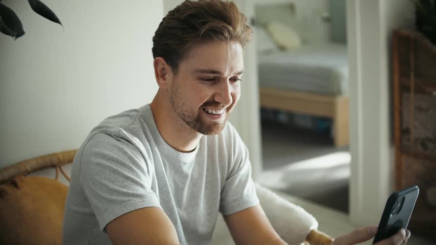 Man smiles and talks as he looks at his mobile phone