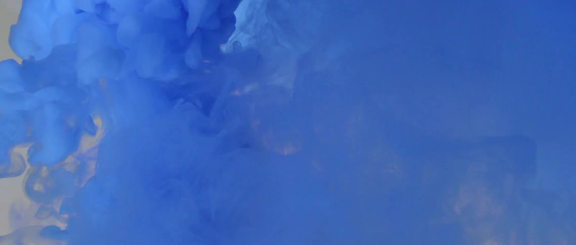 Swirls of bright blue ink floating in a tank of clear water