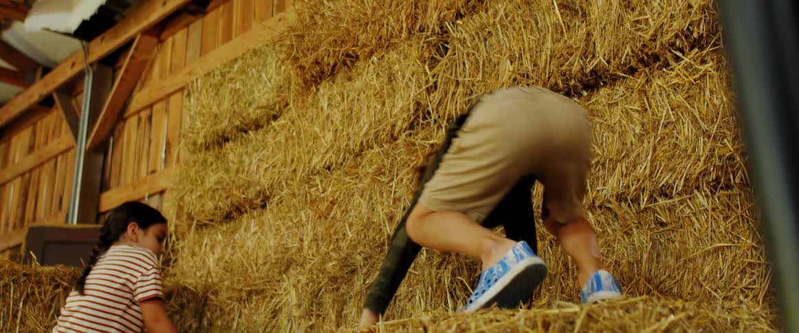 Two children playing in hay bales