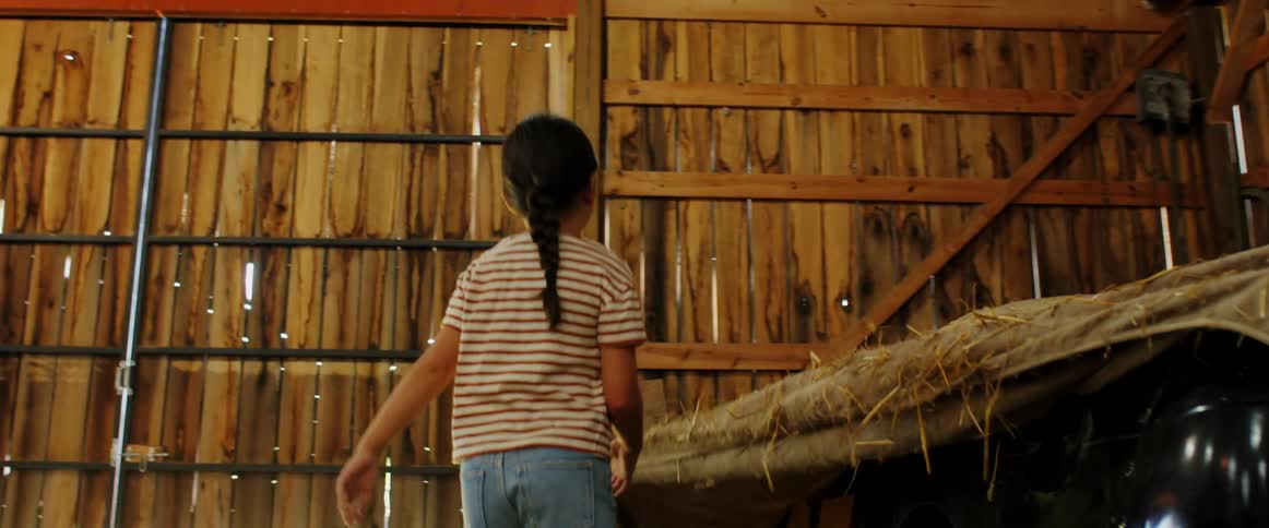 A boy and a girl removing a cover from a vehicle in the garage