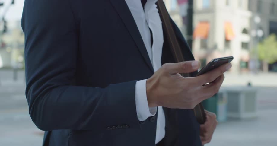 A black man holds his phone and looks at the screen