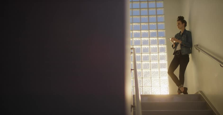 Person standing in a stairway bobbing their head to music