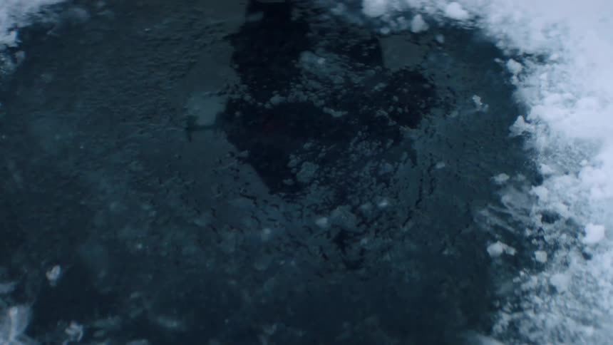 Man approaches the ice on the lake with an auger