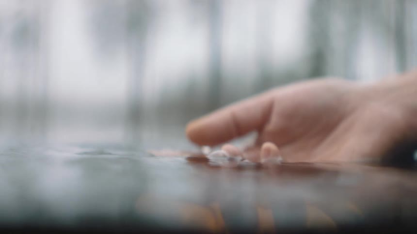 A hand moving gently across the surface of water in a lake