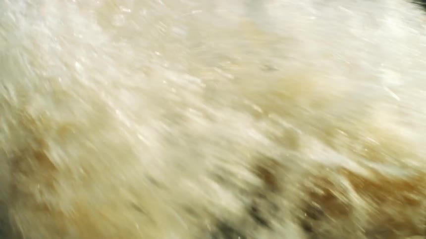 Waves crash against a rock in a river
