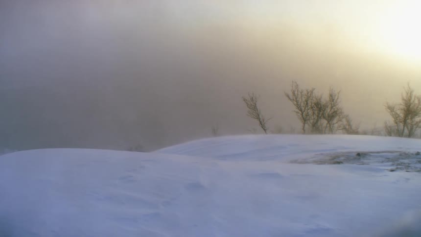 Snow falling over the hills at sunset