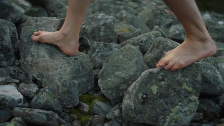 A person barefooted walking on rocks