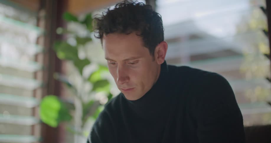 A man is using a laptop and writing in a notebook