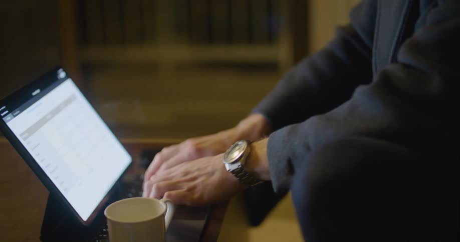 A man leans over his laptop computer while typing and using its touchscreen