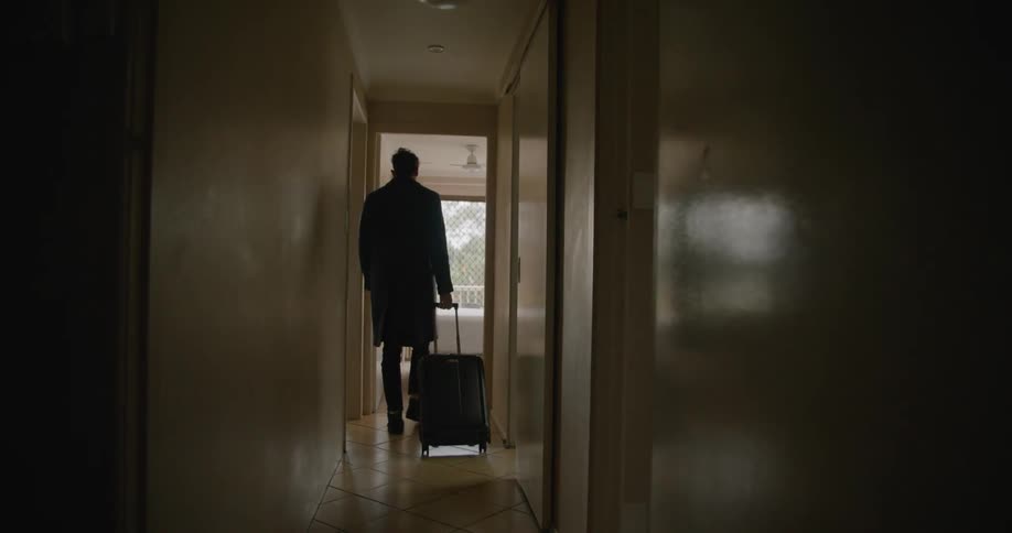 Man carrying luggage enters his room in a hotel