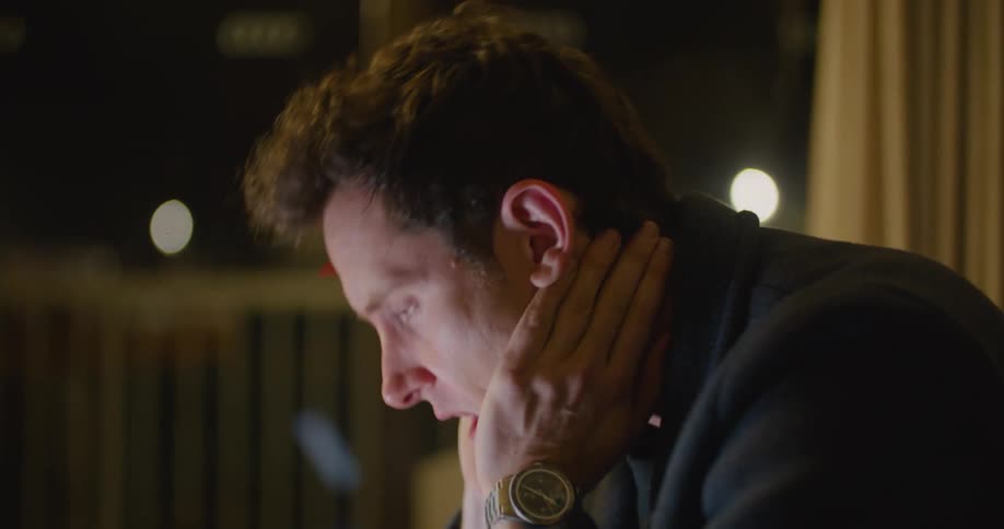 Man takes a drink from a mug then rubs his eyes and yawns