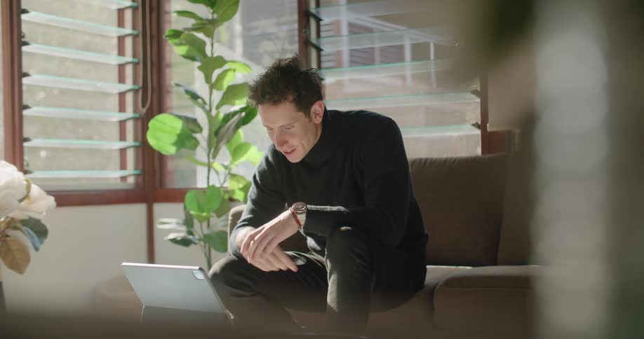 A man sits at home and video chats on his laptop