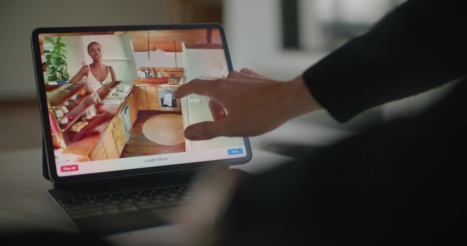 A man talks to a woman on his tablet while virtually designing a layout for a kitchen