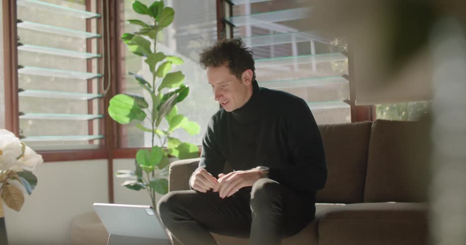 A man is using his laptop on the couch