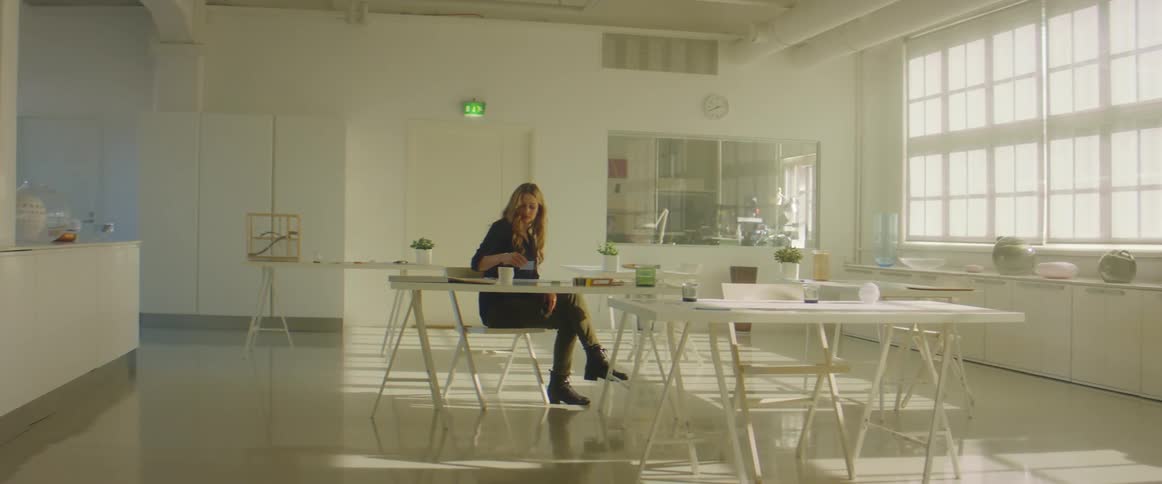 A woman sits down at a table in a room with several empty tables