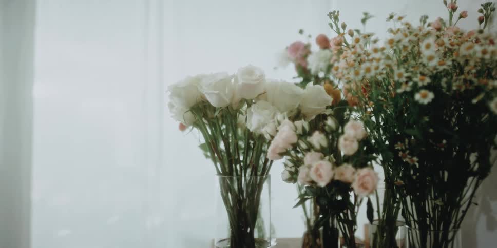 A woman is putting a vase of flowers on a dresser