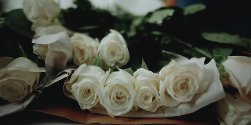 White roses are stacked on paper in a florists shop