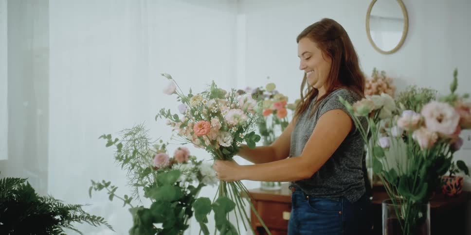 Woman smiles as she creates a bouquet of flowers