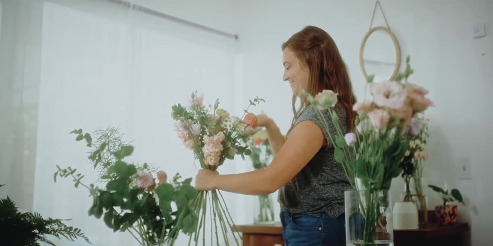 A smiling florist arranging flower bouquets indoors