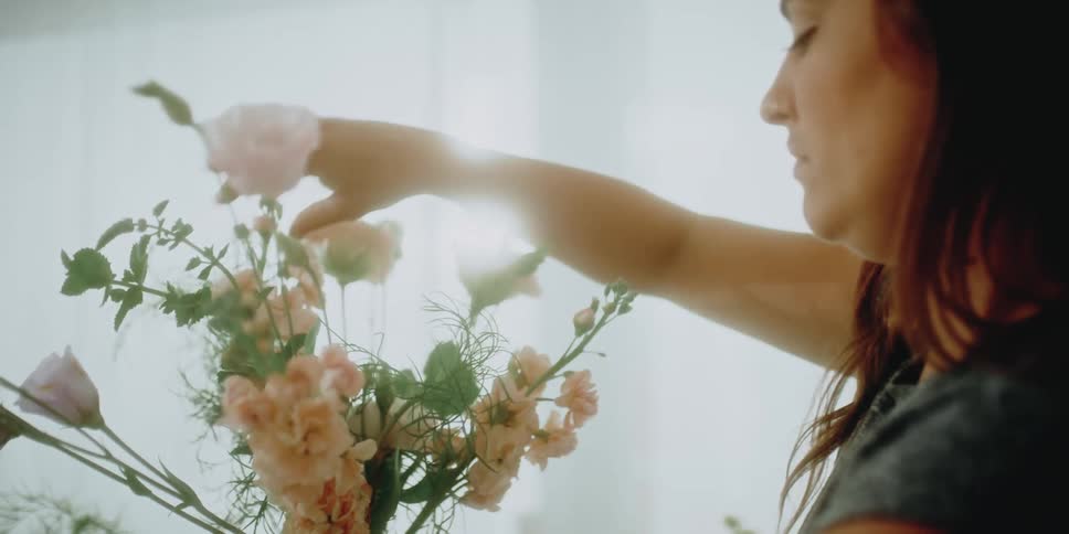 A florist puts the finishing touches on an arrangement in a glass vase