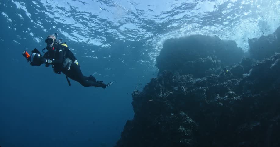 A diver is operating a camera underwater
