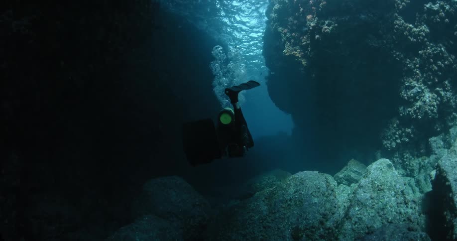 A diver is swimming between two rocks