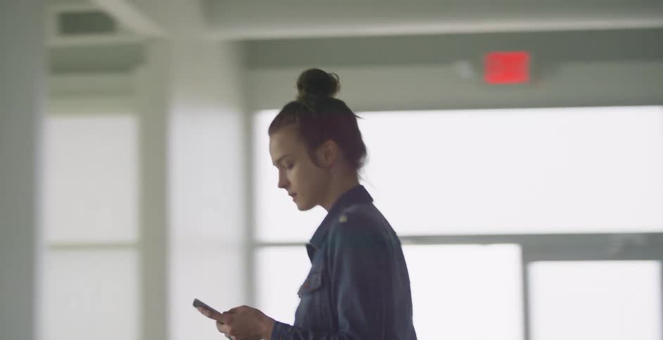 A woman walks down a hallway using a phone