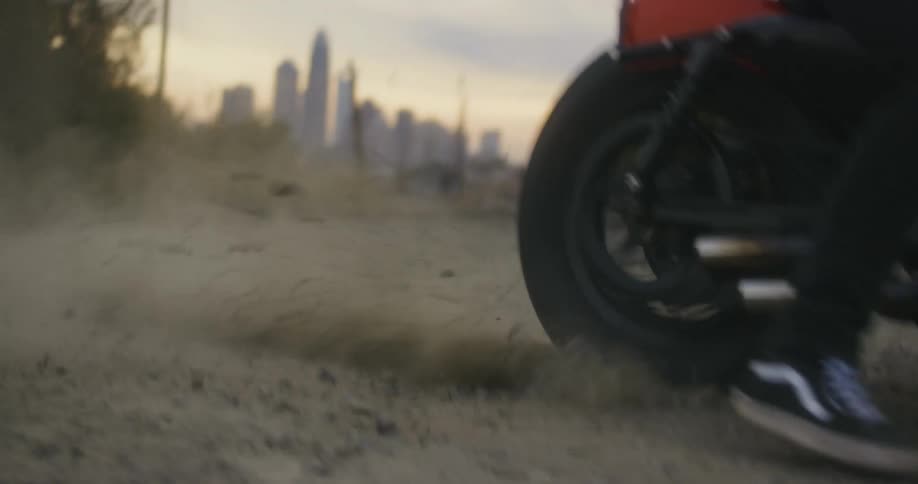 Motorcycle rider spins the tire which kicks up the dirt