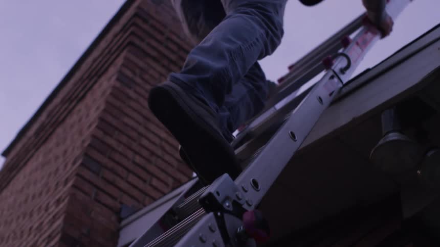 A man is climbing a ladder onto the roof