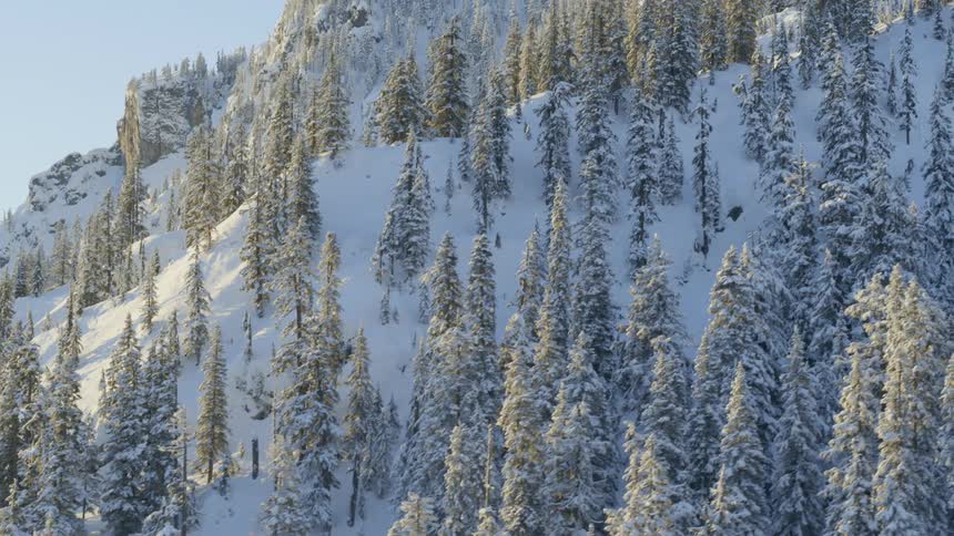 Sunshine rakes across a snow covered mountain ridge on a crisp winter morning