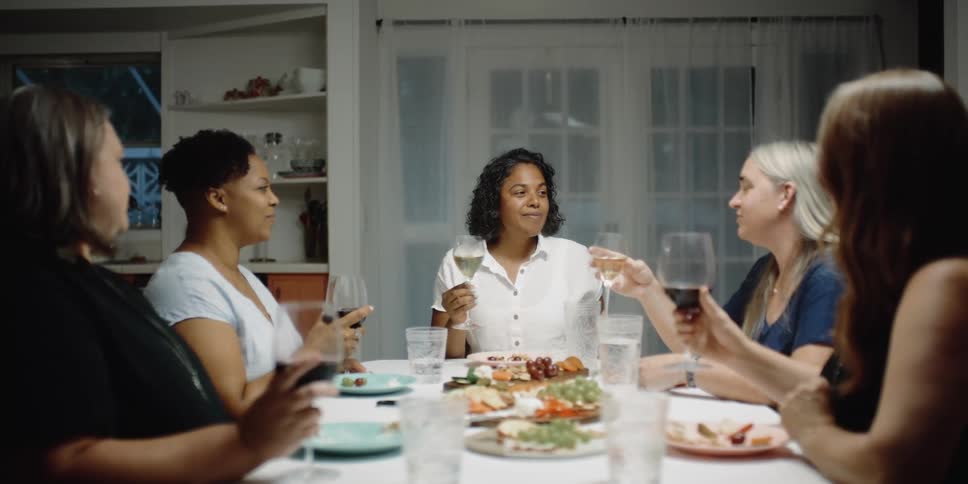 Women in a room sitting at a dining table holding glasses with a door in the background