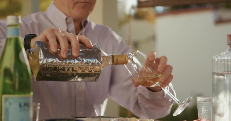 Man sitting at the table pouring liquor on a glass at home