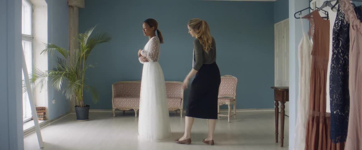 A woman is being fitted for a wedding gown in a shop